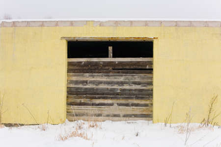 The facade of a small yellow one-story building, the entrance of which is closed with boards. Minimalism in architecture.の写真素材