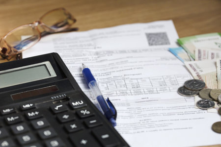 On the table is a receipt for payment, a pen, glasses, money, and a calculator for counting money. Russian banknotes and coins of different denominations. Finance concept.の写真素材