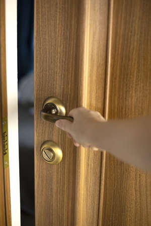 A man opens an interior wooden door. The man opens the door.