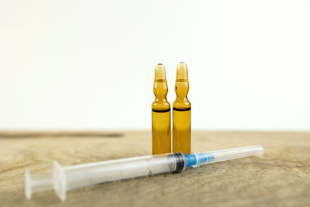 Medical background. Syringe and two medicine ampoules on a wooden table, light background and copy...