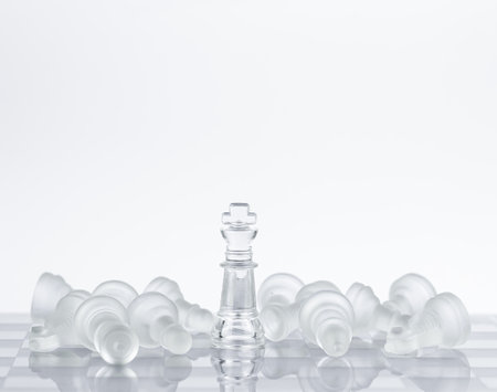 Chess on a glass table, pieces lying around the queen. Defeated chess pieces with copy space. Conceptual photography, board gameの写真素材