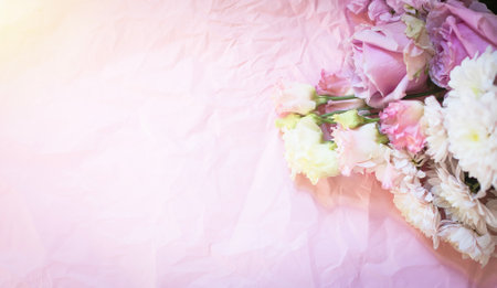 Bouquet of beautiful flowers on a pink background with space for copy. Beautiful banner with white, blue, pink flowers on crumpled wrapping paper. Delicate purple roses, eustomas, chrysanthemumsの写真素材