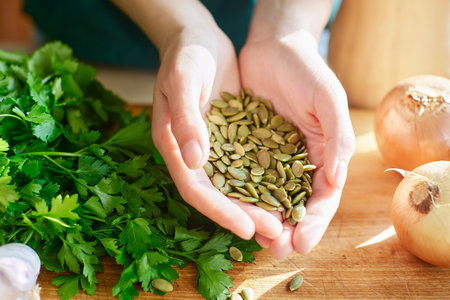 Peeled pumpkin seeds in the palms of your hands against the background of a wooden table, fresh...