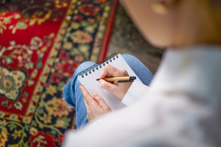 Woman in white shirt and blue pants writing with pen in notebook, psychologist, teacher. Top view of...