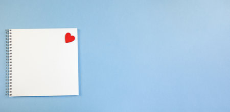 Spring-loaded notebook with square white sheets and a red heart on a blue background. Notebook Blank for Notes, Space for Copy, Text and Advertising, Banner, School Notebook, Business, Blank Sheetの写真素材