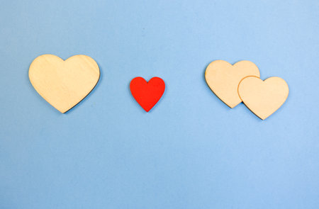 valentine themed wooden heart arrangement, decorative hearts on tranquil blue background create serenity, calm and charming heart arrangement featuring wood and red elements on blue backdropの写真素材