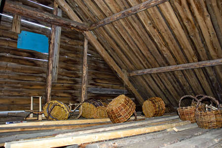 Wicker baskets under the roof of a wooden houseの写真素材