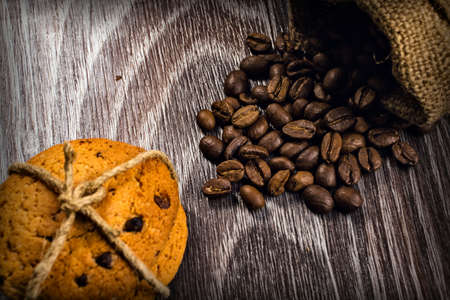 Coffee beans in a bag and cookies on a wooden backgroundの写真素材
