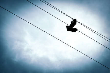 sneakers on electric wires against the skyの写真素材