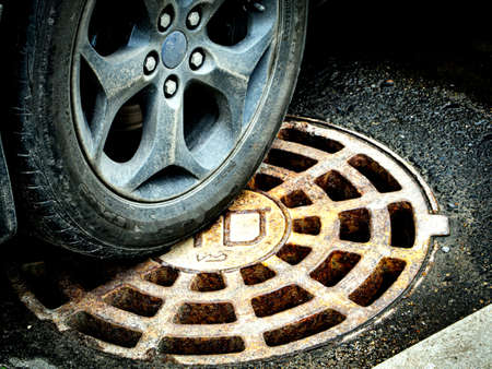 Wheel of a car on a sewer hatchの写真素材