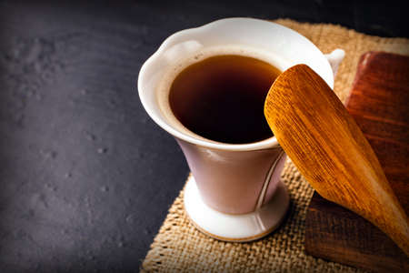 cup of coffee on fabric and a spoon made of wood on a dark backgroundの写真素材