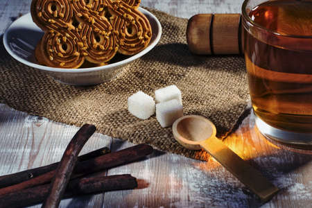 still life with tea mug, sugar and cookies on a wooden tableの写真素材