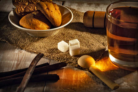 still life with tea mug, sugar and cookies on a wooden tableの写真素材