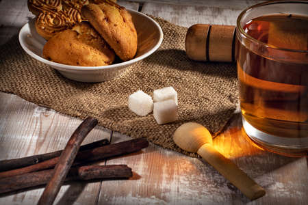 still life with tea mug, sugar and cookies on a wooden tableの写真素材
