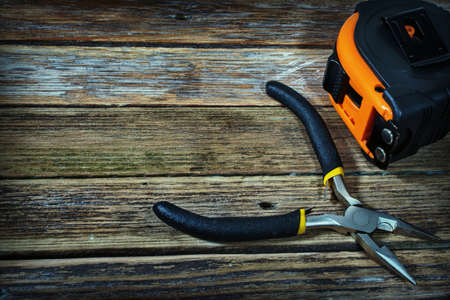tape measure and pliers on a wooden backgroundの写真素材