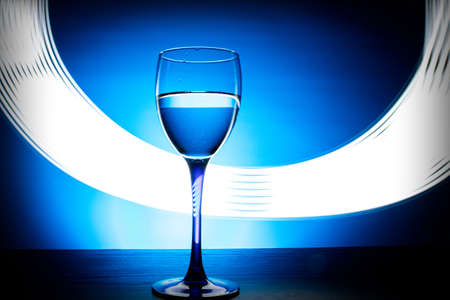 wine glass with water on a blue background with luminous linesの写真素材