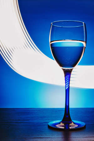 wine glass with water on a blue background with luminous linesの写真素材