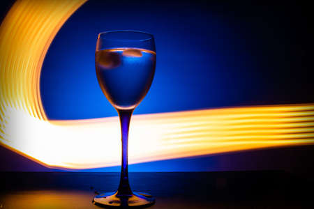 wine glass with water on a blue background with luminous linesの写真素材