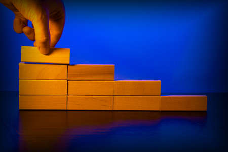 Hand stacking wooden blocks in the form of stairs. Business concept for process growth success.の写真素材