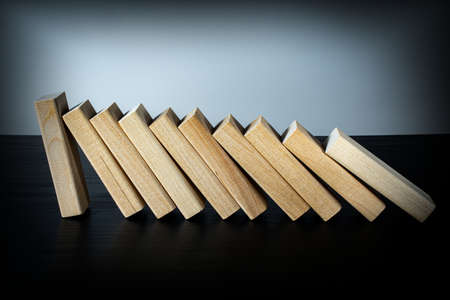 A wooden block stops the fall of other parts of the domino effect. Business risk management concepts.の写真素材