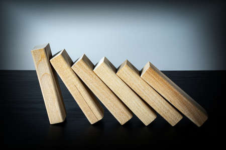 A wooden block stops the fall of other parts of the domino effect. Business risk management concepts.の写真素材