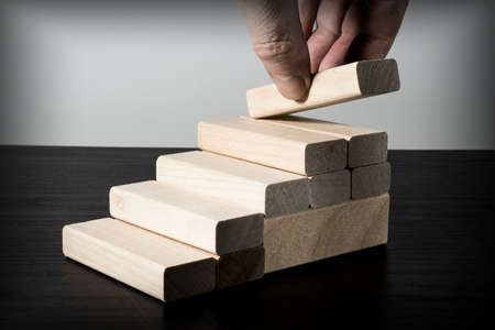 Hand stacking wooden blocks in the form of stairs. Business concept for process growth success.の写真素材