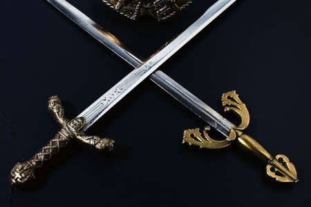 two crossed knightly swords on a black backgroundの写真素材