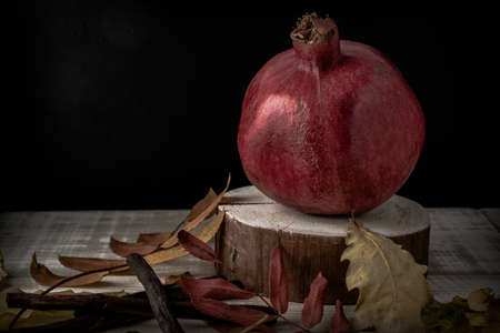 Autumn still life with pomegranate and fallen leaves on a wooden backgroundの写真素材