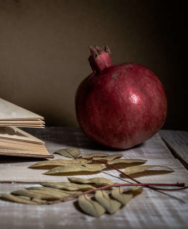 Open book, pomegranate and autumn leaves on a wooden table. Autumn still life.の写真素材