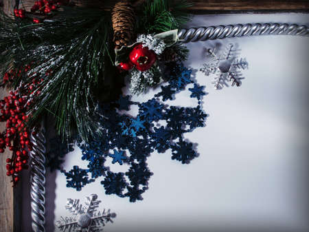 Christmas background with fir branches, cones, a bunch of red berries, candles and snowflakes.の写真素材