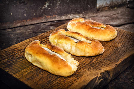 Homemade fish pies on a wooden textured surface against a background of stove brickworkの写真素材