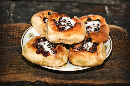 Homemade open pies with berry filling in a plate on a wooden textured surfaceの写真素材