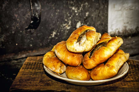 Homemade fish pies on a wooden textured surface against a background of stove brickworkの写真素材