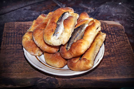 Homemade fish pies on a wooden textured surface against a background of stove brickworkの写真素材