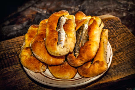 Homemade fish pies on a wooden textured surface against a background of stove brickworkの写真素材
