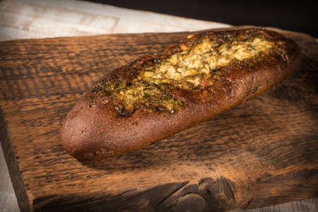 Rye baguette with garlic sauce and dill on a dark textured wooden surfaceの写真素材