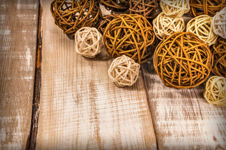decorative rattan balls of different sizes lie on a light wooden surfaceの写真素材
