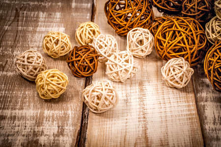 decorative rattan balls of different sizes lie on a light wooden surfaceの写真素材