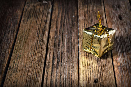 Gold gift box with gold thread on a wooden backgroundの写真素材