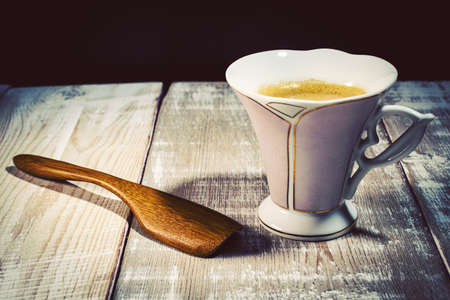 cup of coffee and wooden spoon on tableの写真素材