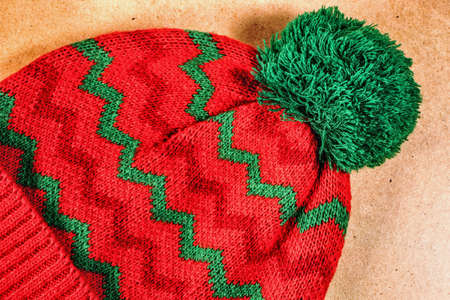 Knitted red hat with green ornament on a wooden backgroundの写真素材