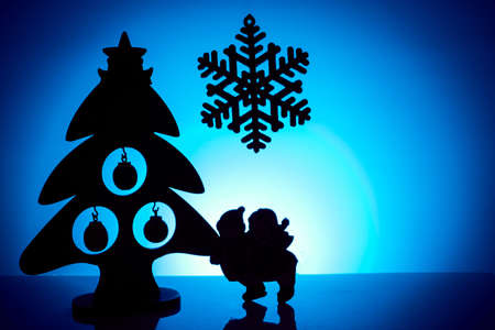 Silhouettes of Christmas tree, snowflakes and children on a blue background.の写真素材