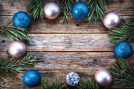 Christmas balls and pine branches arranged in a circle on a wooden background. Winter holiday concept. View from above. Copy spaceの写真素材