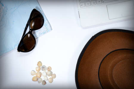 White laptop, map, seashells, hat and sun glasses on a white background. View from aboveの写真素材