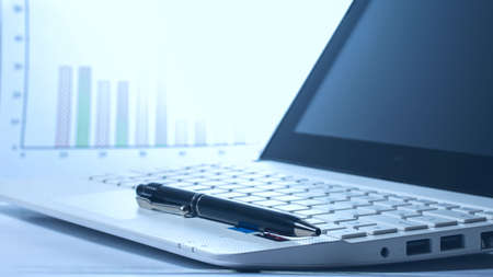 Open laptop and pen on the background of the profit graph. Back light. Business conceptの写真素材