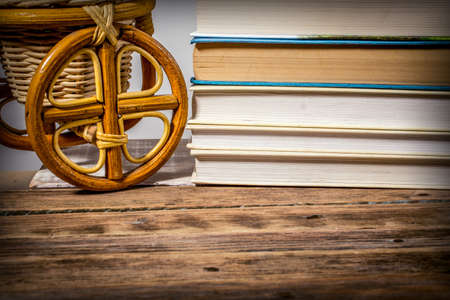 A stack of books and a wicker willow product on a wooden tableの写真素材
