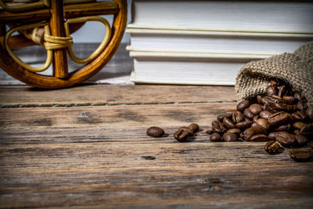 Background with scattered coffee beans on a wooden table with booksの写真素材