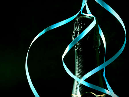 Bottle of champagne wine close-up and blue serpentine on a dark blue background. Holiday concept. Copy spaceの写真素材