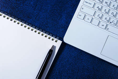 White notebook, spring bound notebook and pen on a blue background. Close-upの写真素材