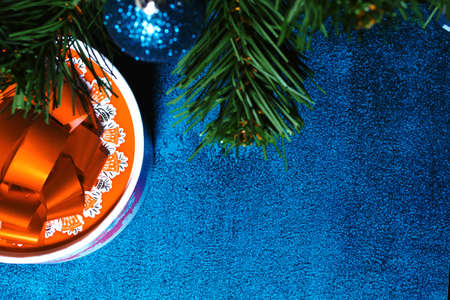 Christmas blue ball, spruce branches and a gift with a red ribbon in the form of a bow on a blue background. Copy spaceの写真素材